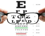 Okulary przesłaniające tablicę Snellena. Litery są rozmazane, co może sugerować za mocne okulary objawy.