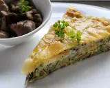 Kawałek zapiekanki z cukinii z warzywami i serem, podany z miseczką pieczarek.