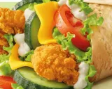 McWrap Bekon Deluxe: chrupiący kurczak, bekon, ser, warzywa i sos w tortilli. Pyszny i sycący, idealny na szybki posiłek.