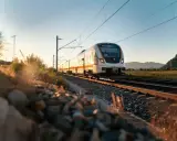 Treno moderno su binari al tramonto, ideale per capire come spostarsi da Porto a Lisbona in modo panoramico e rilassante.