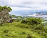 Zwei Wanderer genießen die Aussicht auf die Küstenstadt Irun, Spanien, von einer alten Ruine aus.