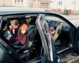 Niños en asientos de coche, uno con gorro naranja. Guía visual para como colocar silla grupo 2 3 sin isofix.