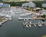 Viele Segelboote und Yachten liegen im dampfenden Hafen von Damp. Moderne Gebäude säumen die Küste.