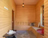 Interior de madera con bancos para relajarse, mostrando varios tipos de saunas. Un sombrero rojo y cojines decoran el espacio.