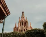 Imponująca iglica kościoła w San Miguel, otoczona zielenią, z ozdobnymi gwiazdami zwisającymi z zadaszenia.