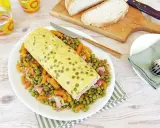 Rotolo di frittata dorato adagiato su un letto di piselli e carote. Un piatto semplice e gustoso, perfetto per un pasto leggero.