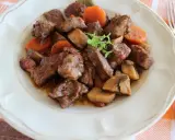 Bœuf bourguignon: duszona wołowina z marchewką i pieczarkami, podana na talerzu.