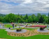 Kolorowy park z rzeźbami z kwiatów i zieleni. Widać ludzi spacerujących alejkami. Sprawdź góra parkowa cennik, by zaplanować wizytę.