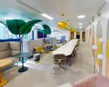 Espace de travail moderne et coloré, ce **flex office** offre des zones de réunion, des canapés confortables et des plantes décoratives pour un environnement stimulant.