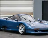 Blauer Jaguar XJR-15 Sportwagen mit auffälligem Heckspoiler und glänzenden Felgen, bereit für die Rennstrecke.