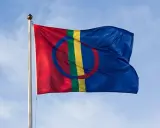 Samiska flaggan vajar stolt mot en blå himmel, en symbol för samiska nationaldagen och ett folk med djupa rötter.