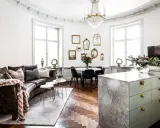 Ett vardagsrum med mörk soffa, marmorö, och en matplats. Massor av speglar på väggen ger inredning inspiration.