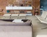 Soggiorno moderno con divano grigio, poltrone in pelle bianca e sgabelli, su sfondo di travertino rosso. Il **case design** è elegante e funzionale.