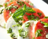 Salade Caprese : fines tranches de tomates rouges et de mozzarella crémeuse, parsemées de basilic frais. Une recette simple et savoureuse.