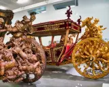 Prunkvolle Kutschen im Kutschenmuseum Lissabon: Eine aus Holz geschnitzte, die andere golden verziert, beide mit aufwendigen Figuren.