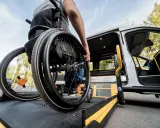 Osoba na wózku inwalidzkim wjeżdża na platformę windy. Dowiedz się, jak załatwić wózek inwalidzki i zapewnić sobie mobilność.