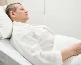 Mężczyzna w białym szlafroku leży w szpitalnym łóżku, przygotowując się do usunięcia pęcherza moczowego.