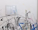 Paredes blancas con garabatos de colores y un interruptor sucio. ¡Hora de limpiar paredes!