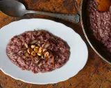 Risotto rosso con cipolla caramellata e nocciole, un classico tra i piatti tipici di Verona, servito su un piatto bianco con un cucchiaio d'argento.