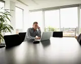 Mężczyzna w okularach rozmawia przez telefon, pracując na laptopie. Planuje koszty uzyskania przychodu 2025.