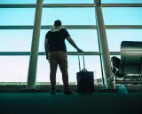 Mężczyzna z walizką czeka na lotnisku w Modlinie. Ile jeszcze do odlotu?