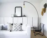 En stilren och modern manlig inredning med vit soffa, svarta detaljer och en golvlampa.