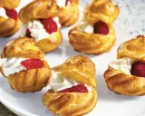 Små petit choux fyllda med vispgrädde och toppade med hallon eller jordgubbar. En härlig dessert!