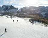 Narciarze szusują po ośnieżonym stoku w Dolomitach. Idealne miejsce, gdzie na narty we Włoszech, z majestatycznymi górami w tle.