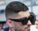Mann mit stylischem Crew Cut und Sonnenbrille, der nachdenklich in die Ferne blickt.