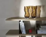 Två bärnstensfärgade glasvaser på en hylla, bredvid böcker och en röd ljushållare. Även böcker med texten HEIN STUDIO syns.