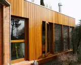 Modern house with ventanales grandes para casas, madera y ladrillo. Un árbol frondoso cuelga sobre la estructura.