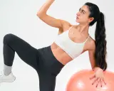 Frau macht Übungen mit Gymnastikball. Sie fragt sich, was ist Kreatin, während sie ihre Muskeln trainiert.