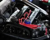 Motor de coche con tapa de válvulas "16 VALVE", cables rojos y correa de distribución.