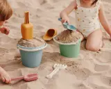Niños disfrutando de juegos en la playa con cubos y palas de arena.