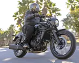 Mężczyzna w kasku jedzie czarnym motocyklem Kawasaki EN 500. Wady i zalety tego modelu są dyskutowane podczas jazdy wśród palm.