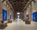 Vaste salle d'exposition à Venise, avec des œuvres d'art bleues et des sculptures en pierre. L'architecture industrielle de Pinault Venise est mise en valeur.