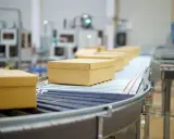 Pudełka na taśmie transportowej w magazynie ecommerce.