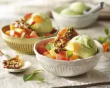Deliciosos postres saludables: helado verde cremoso con trozos de melón, papaya y un toque crujiente de pistachos.