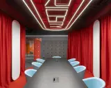 Aménagement salle de réunion moderne avec table noire, fauteuils bleus, rideaux rouges et éclairage néon au plafond.