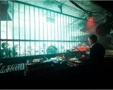 DJ set in un locale underground, luci al neon e folla che balla dietro le sbarre. Atmosfera da berlino rave.