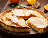 Une délicieuse tarte à l'orange, garnie de fines tranches d'agrumes et saupoudrée de sucre glace, sur un fond de bois rustique.