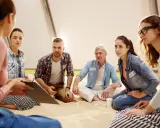 Grupa ludzi na sesji psychoterapii grupowej yalom. Siedzą w kręgu, słuchając siebie nawzajem.