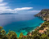 Un angolo di paradiso dove in Toscana c'è il mare. Acque cristalline lambiscono una costa rocciosa, con case dai tetti rossi immerse nel verde.