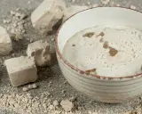 Aktywny rozczyn z drożdży w misce, obok kostki świeżych drożdży i okruszki.