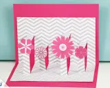 Eine pinke Pop-up-Karte basteln mit Blumen auf grau-weißem Zickzack-Muster.