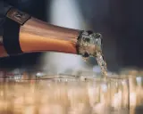 En flaska hälls upp i glas, det ser ut att bli gott bubbel.
