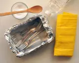 Czyszczenie sztućców sodą: folia aluminiowa, soda, woda i żółta ściereczka.
