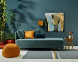 Ein Wohnzimmer mit einem türkisfarbenen Sofa, orangefarbenen Akzenten und einem abstrakten Gemälde. Die Wandfarbe könnte die Farbe des Jahres 2026 sein.