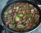 Ein deftiges schnippelbohnen rezept mit Kartoffeln und Würstchen in einer Pfanne.