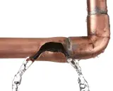 Fuite d'eau sur un tuyau en cuivre endommagé. Une solution pour réparer tuyau cuivre sans soudure est nécessaire.
